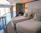 Ecco cosa trovo in cabina MSC: due letti singoli, una poltrona blu, quadri astratti e una grande finestra con vista panoramica.