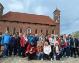 Grupa turystek pozuje na tle imponującego zamku biskupów warmińskich w Lidzbarku Warmińskim.