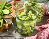 Schnellgurken rezept ohne kochen: Frische Gurkenscheiben mit Dill und Senfkörnern in Gläsern, bereit zum Einlegen.