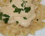 Makaron farfalle polany kremowym sosem serowym i posypany natką pietruszki.