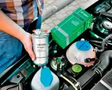 Wymiana filtra paliwa w Citroen C4 1.6 HDI. W ręku trzymany jest filtr Filtron PP 839/1, obok zielone opakowanie.