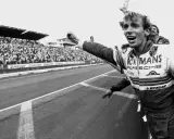 Jubelnder Stefan Bellof im Rennanzug mit "Le Mans" und "Porsche" Aufschrift, jubelnde Menge im Hintergrund.