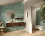 Elegante bagno verde petrolio e legno con lavabo in pietra, specchio rotondo e bidet sospeso.