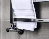 Nowoczesny grzejnik łazienkowy, jeden z wielu rodzajów grzejników, z białymi ręcznikami.