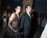 Dua Lipa stuns at the Met Gala in a black feathered gown and diamond necklace, walking with a companion.