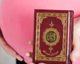 Schwanger, hält eine Frau den Koran. Im Islam gibt es Erleichterungen beim Fasten während der Schwangerschaft.
