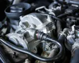 Primer plano del motor de un coche, mostrando el alternador y otras piezas. Podría ser la causa de un fallo alternador coche.