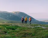 Tre vänner på vandring i Idre njuter av den vidsträckta fjällnaturen i solnedgången.