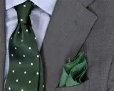 Zielony krawat w kropki do niebieskiej koszuli i szarej marynarki. Elegancka stylizacja.