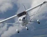 Eine weiße Cessna Skyhawk fliegt durch bewölkten Himmel. Der Pilot blickt aus dem Cockpit.