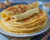 Ein Stapel goldbrauner Eierkuchen, zwei davon gerollt, perfekt für ein einfaches Eierkuchen Rezept.