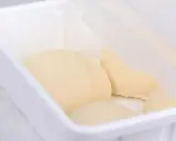 Pâte à pain trop fermenté dans une boîte blanche, prête pour la cuisson.