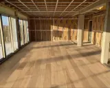 Pose de parquet clair dans une pièce en construction, le sens des lames semble agrandir l'espace.