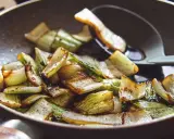 Gebratener Mangold und Pak Choi in einer Pfanne, leicht karamellisiert und mit einem Löffel serviert.