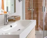 Bagno moderno con lavabo bianco, rubinetteria cromata e doccia con piastrelle color terra. Ideale per misure minime mini bagni piccoli progetti.