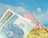 Pieniądze na plaży, leżak i błękitne niebo. Czy to symboliczne przedstawienie opłaty klimatycznej za wakacyjny wypoczynek?