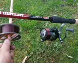 Wędka Method Feeder i kołowrotek z ciemną żyłką. W dłoni szpulka z żyłką, idealna do method feeder.