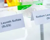 Zwei Schalen mit weißen Pulvern, beschriftet mit "Sodium Laureth Sulfate (SLES)" und "Sodium Lauryl Sulfate (SLS)". Diese Inhaltsstoffe sind oft in SLS-Shampoos zu finden.