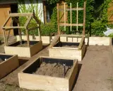 Un nouveau modèle de jardin potager en bois, prêt à accueillir les plantations. Des carrés surélevés avec des structures pour plantes grimpantes.