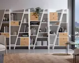 Estanterías blancas con cajones de madera, llenas de libros y objetos decorativos. La decoración de estanterías es clave para un hogar moderno.