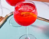 Ein erfrischender Campari Spritz mit Eis und Orangenscheibe auf einem Tablett.