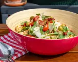 Leckere nudelsalat ideen: Pasta mit Rucola, Tomaten, Oliven und Parmesan in einer roten Schüssel.