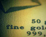 Zbliżenie na tekst "fine gold 50 g 999,9" wybity na powierzchni złota.