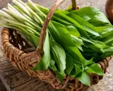 Un panier en osier déborde de feuilles vertes fraîches d'ail des ours, prêt à être cuisiné.