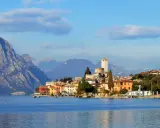 Borgo sul lago di Garda con castello e montagne sullo sfondo. Un luogo incantevole da esplorare, scopri cosa vedere!