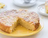 Ein köstlicher Zitronen-Mandelkuchen, perfekt für rezepte mit mandelmehl. Mit Mandelblättchen und Puderzucker bestreut, daneben frische Zitronenspalten.