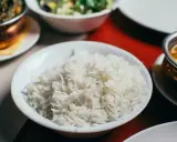 Biały ryż, źródło węglowodanów, w misce obok indyjskiego curry i sałatki.