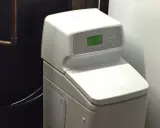 Adoucisseur d'eau blanc avec écran vert, un avantage pour une eau plus douce et une maison protégée.