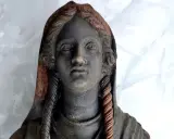 Statua antica ritrovata nel santuario di San Casciano dei Bagni, con capelli intrecciati e volto enigmatico.