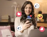 Ung kvinna ler när hon använder sin telefon, omgiven av sociala medieikoner som hjärtan och tummen upp. Hon upplever positiva saker med sociala medier.