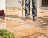 Nettoyer carrelage extérieur noirci avec un nettoyeur haute pression. L'eau projetée révèle la beauté naturelle des dalles.