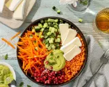 Bunter rote Linsen Salat mit Gurke, Karottenstreifen, Granatapfelkernen, Avocado-Dip und Brie-Käse.