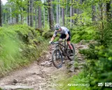Kolarz MTB pokonuje kamienisty zjazd w lesie. To fragment kalendarza MTB, pełnego adrenaliny i pasji.