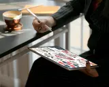 Kobieta z kawą i tabletem, na którym widać schemat dotyczący pracy w Norwegii.