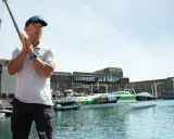 Un homme applaudit devant le trimaran Sodebo Ultim 4, prêt à naviguer.