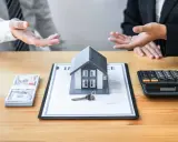Negociación de honorarios inmobiliaria: casa modelo, llave, dinero y calculadora sobre un contrato.