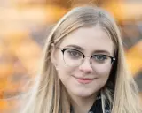 Uśmiechnięta blondynka w okularach, idealna do portretów. Taki obiektyw do portretów pozwala uchwycić subtelne detale.