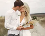 Para młoda całuje się na tle pola. Wiek nie ma znaczenia, gdy miłość jest prawdziwa.