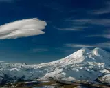 Elbrus szczyt w chmurach lenticularnych. Majestatyczne, ośnieżone góry pod błękitnym niebem.