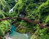 Sentiero panoramico tra gole e cascate, un esempio di posti strani da visitare in Italia, con passerelle in metallo che si snodano tra la vegetazione lussureggiante.
