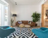 Brun soffa, turkosa fåtöljer och en stor kaktus ger en känsla av inredning 80-tal. Mönstrat golv och trädetaljer.