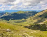 Panoramica dei Monti Sibillini, un paesaggio verdeggiante con dolci colline e valli, ideale per scoprire cosa vedere in questa zona.