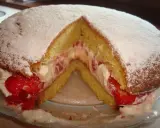 Puszysty biszkopt przełożony kremem i truskawkami, posypany cukrem pudrem. Klasyczny victoria sponge cake.