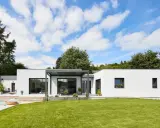 Une maison modulable moderne avec piscine et jardin luxuriant, sous un ciel bleu éclatant.