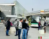 Ludzie czekają na autobus przed Terminalem A na lotnisku w Katanii.