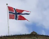 Norwegische Flagge weht im Wind über einem Gebäude. Die Diskussion über den Stromverbrauch in Norwegen ist aktuell.